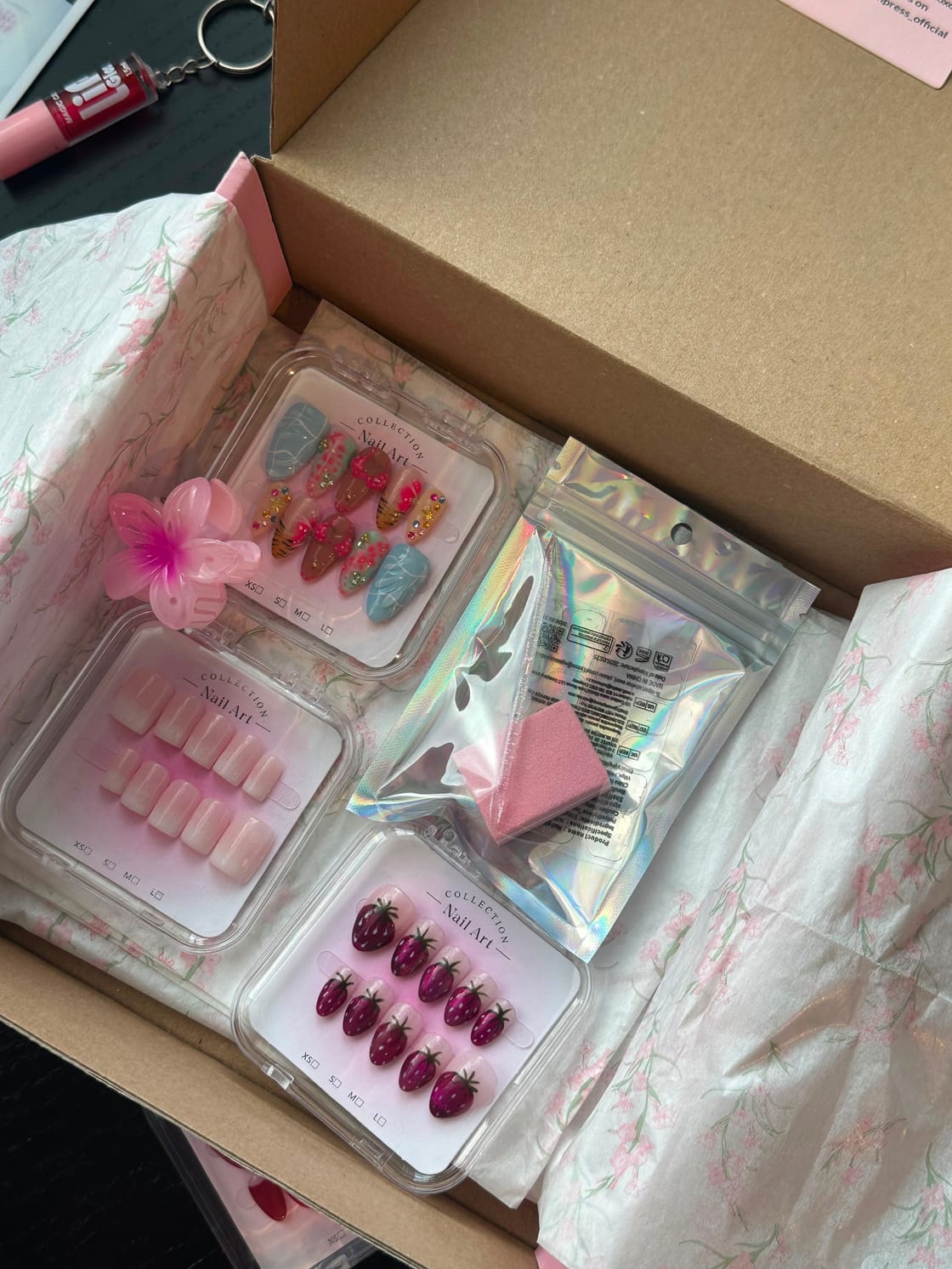 An opened box with press-on sets, a file and the little extras